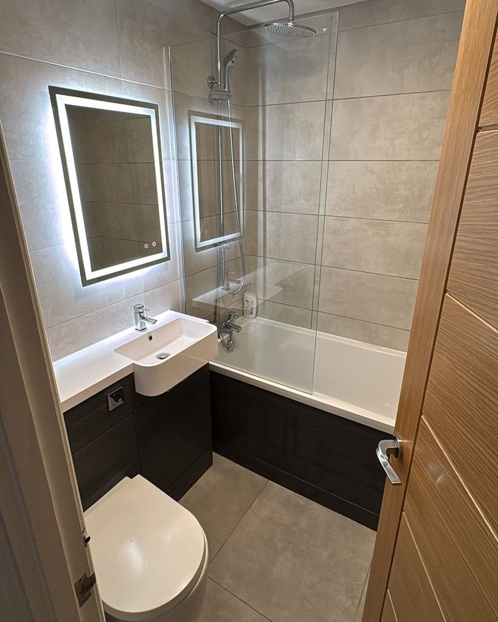 The same bathroom after cleaning with clear surfaces, shining sink, bath and mirror