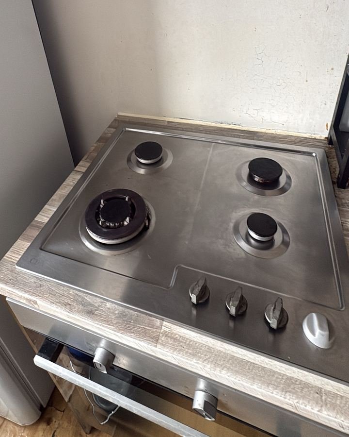 The same gas hob after cleaning, stainless steel restored and wall wiped clean