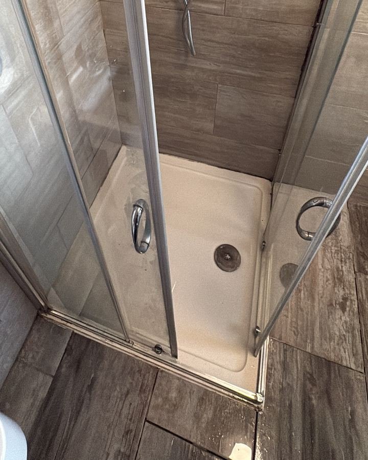 The same shower after cleaning with a bright white tray and clear glass doors